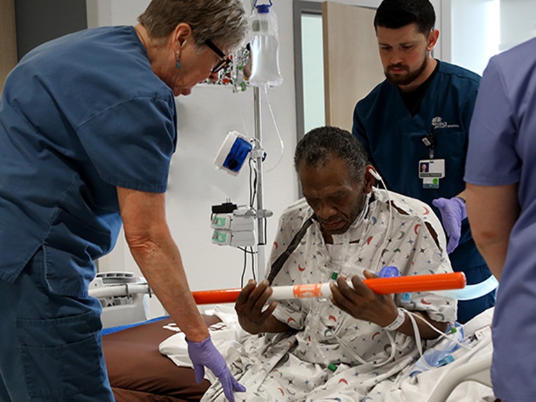 three nurses standing by patient hooked up to medical equipment
